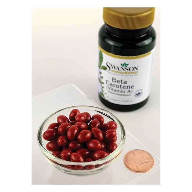 A bowl of red capsules sits next to a Swanson Beta-Carotene (Vitamin A) 10000 IU 250 Softgels bottle, highlighting vision and skin health benefits, with a penny for size reference.