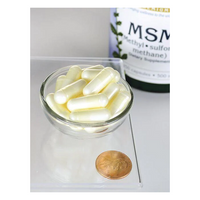 Thumbnail for A glass bowl of white capsules sits on a countertop next to a penny, with a background bottle labeled 