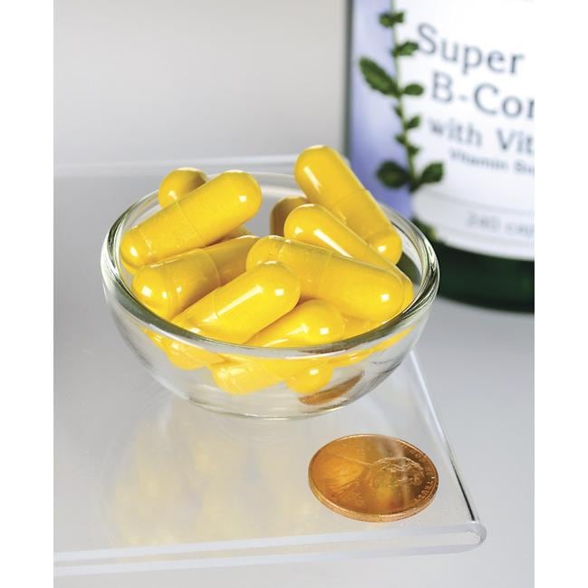 Swanson Gélules de B-Complex avec vitamine C dans un bol à côté d'un penny.