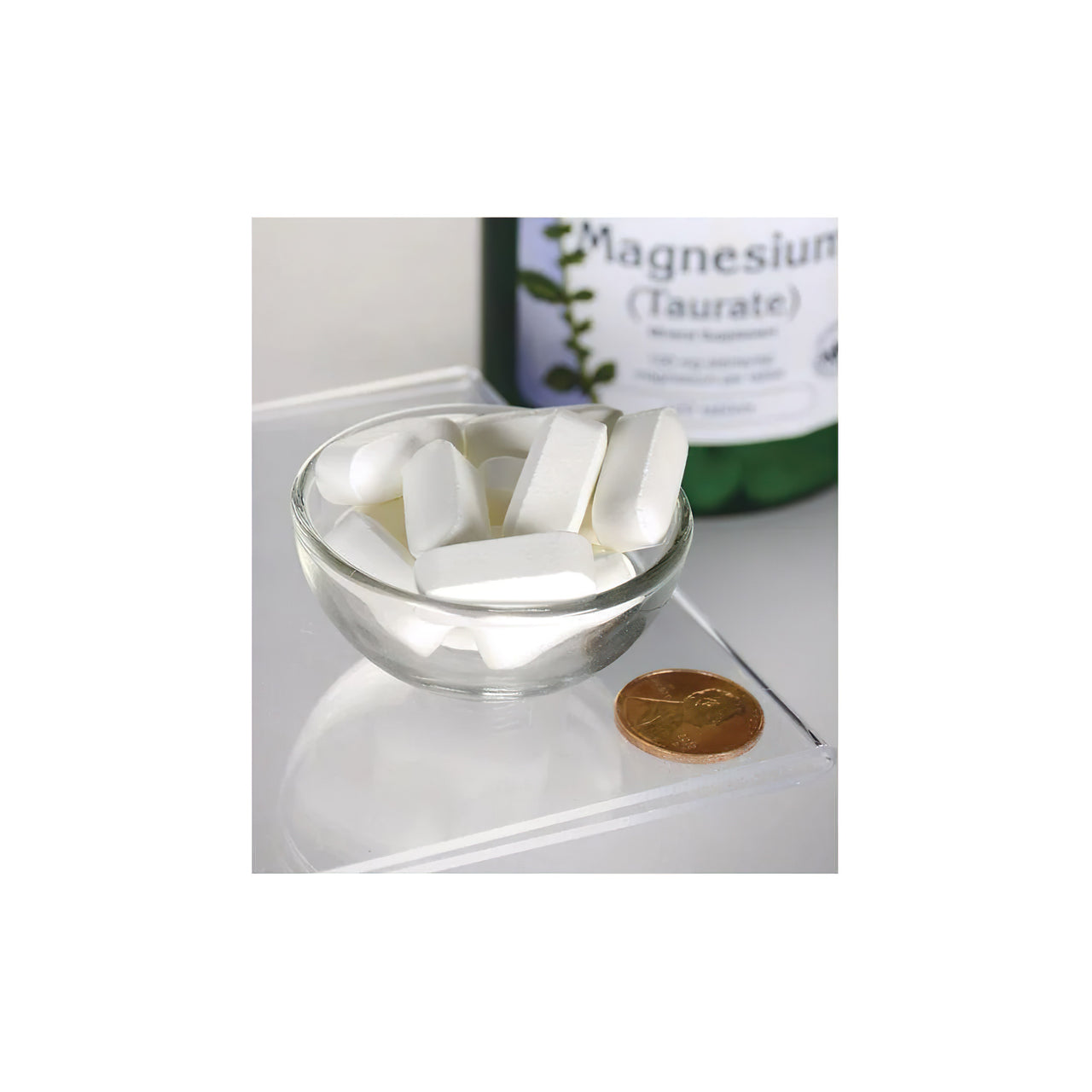 Un flacon de Swanson Magnesium Taurate 100 mg 120 tab à côté d'un bol de pilules blanches.