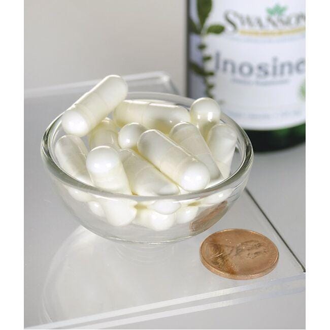 Un bol de pilules blanches à côté d'un flacon de Swanson Inosine - 500 mg 60 gélules végétales.