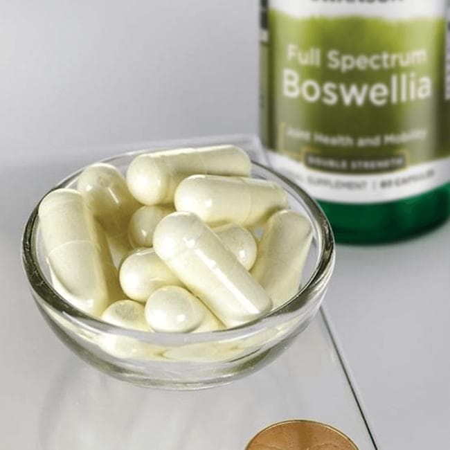 Un complément alimentaire, Swanson Boswellia, est présenté avec 60 gélules à côté d'un centime sur une balance.