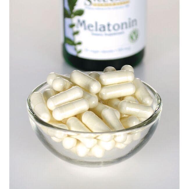 Swanson Mélatonine - 0,5 mg 60 gélules végétales dans un bol en verre à côté d'une bouteille.