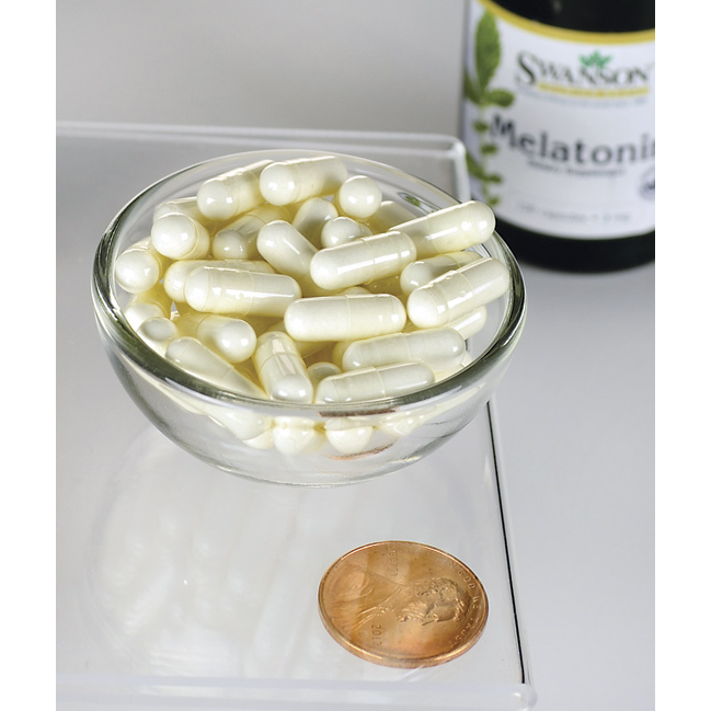 Swanson Racine d'astragale - 470 mg 100 gélules dans un bol à côté d'un penny.