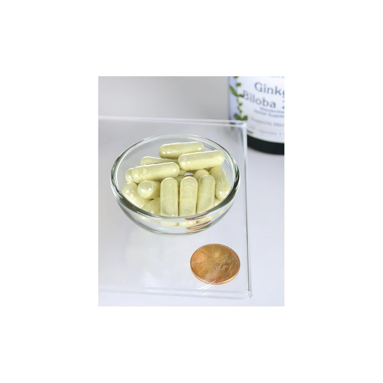Un bol de Swanson Ginkgo Biloba Extract 24% 60 mg 240 cap avec une pièce de monnaie à côté.