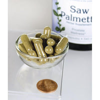Vignette pour Swanson Saw Palmetto - 540 mg 250 gélules, connues pour leur rôle dans la promotion de la santé de la prostate et de l'écoulement des voies urinaires, sont présentées dans un bol à côté d'une pièce d'un centime.
