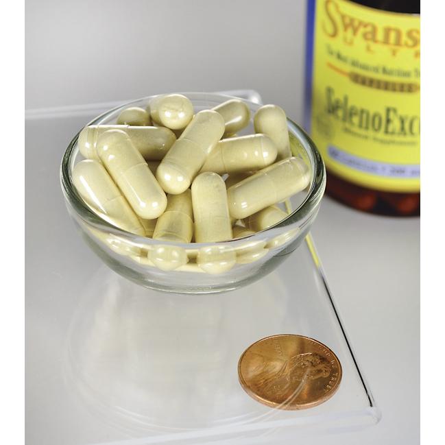 Un flacon de SelenoExcell Selenium - 200 mcg 60 gélules de Swanson et un penny à côté d'un bol de pilules, promouvant les soins cardiovasculaires.