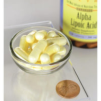 Miniature pour Une bouteille d'acide alpha-lipoïque Swanson - 300 mg 120 gélules se trouve à côté d'une pièce de monnaie.
