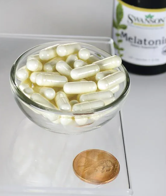 Un bol de Swanson Melatonin - 3 mg 120 gélules à côté d'un penny.